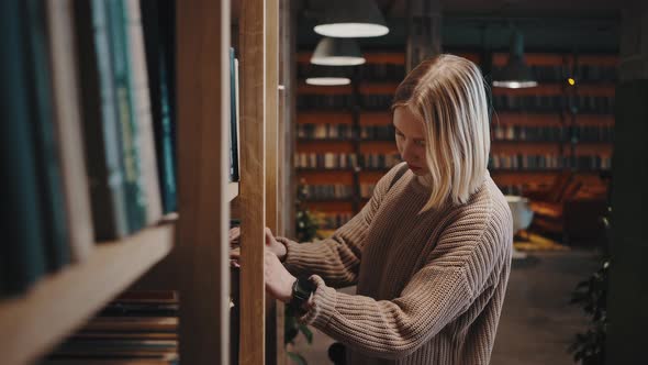 Young Woman Student Coming to Bookshelves in Library and Choosing Book Reading Information Tracking