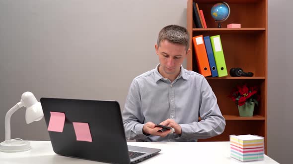 Young Man in His Office Job Cleaning His Smartphone Device