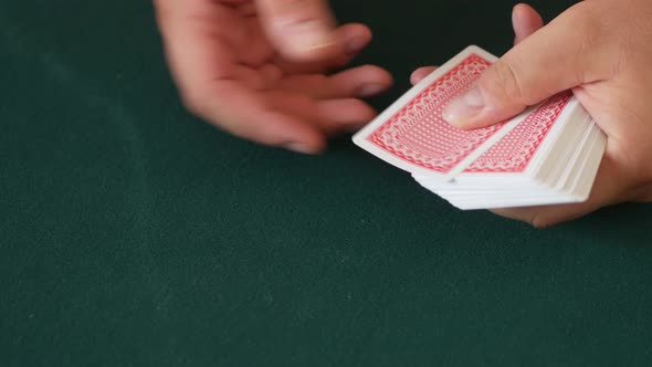 Close-up of a casino dealer's hands as he deals playing cards and then fans out the cards on the tab