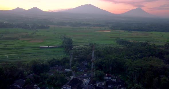 Small town in central Java, Indonesia with 4 mountains in the background during a colorful sunrise.