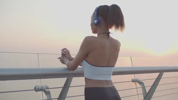 Female Runner in Headphones Enjoying Cityscape at Dawn