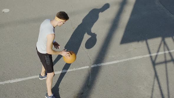 Young Caucasian basketball player dribbling a ball at stadium, sport and hobby