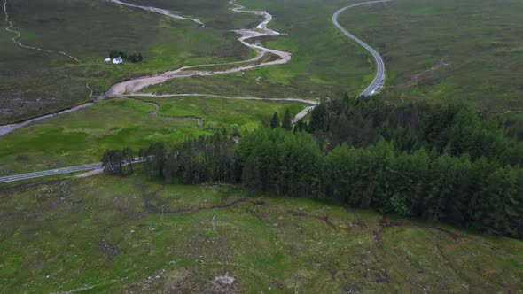 Panning drone shot reveals tress and mountains in cloudy conditions