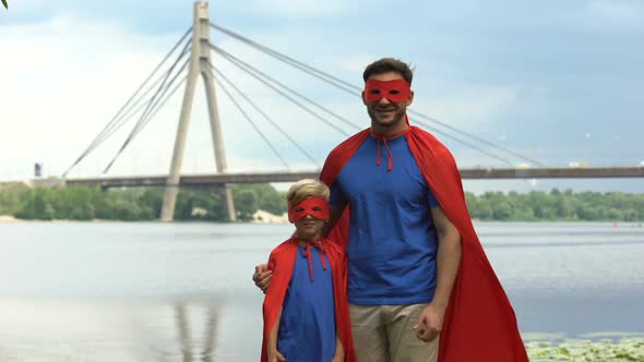 Father and Son in Superhero Costumes Showing Thumbs Up, Motivation and Teamwork