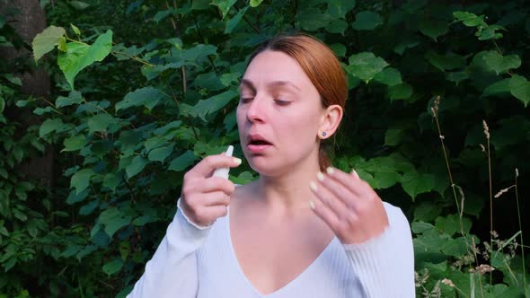 Young Woman Wearing Red Scarf Spraying Nasal Spray Standing in The City Park