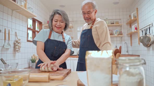 Asian Senior elderly couple cooking foods, enjoy retirement life together in kitchen at home.