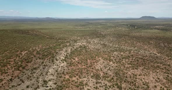 Ascending drone shot of a dry game farm with mountains on the horizon during drought near Okahandja,