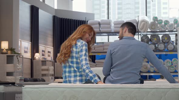 Cheerful Couple Smiling To the Camera, While Choosing New Bed at Furniture Store