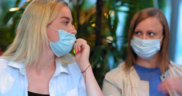 Mom and Daughter Take Off Blue Face Masks Sitting at Restaurant Table