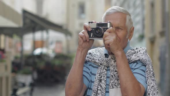 Senior Male Tourist Exploring Town and Makes a Photo with Retro Photo Camera