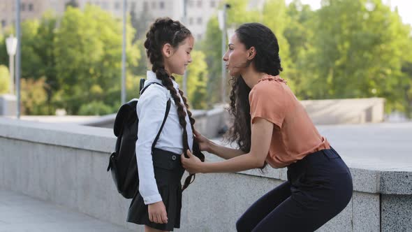 Parent Mother Woman Brunette Straightens Pigtails of Daughter Talking Child Talks Smiling to