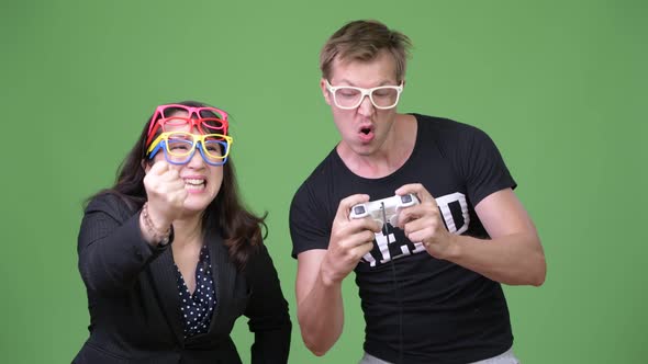 Mature Asian Businesswoman and Young Scandinavian Nerd Man Playing Games Together