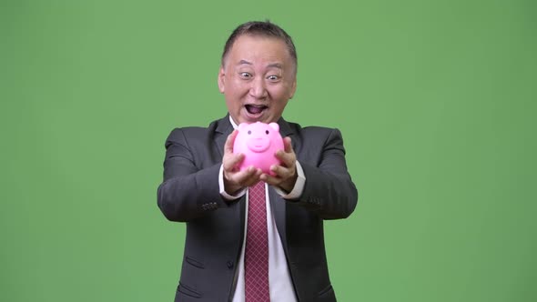 Mature Japanese Businessman Holding Piggy Bank