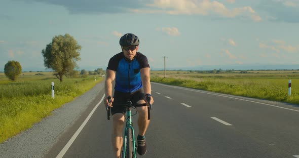 A Cyclist is Riding Along the Highway at a Slow Pace