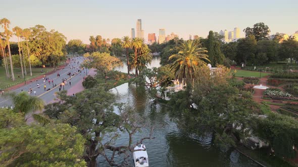 Aerial dolly out of Rosedal gardens pond near Palermo Woods pedestrian street at golden hour, Buenos