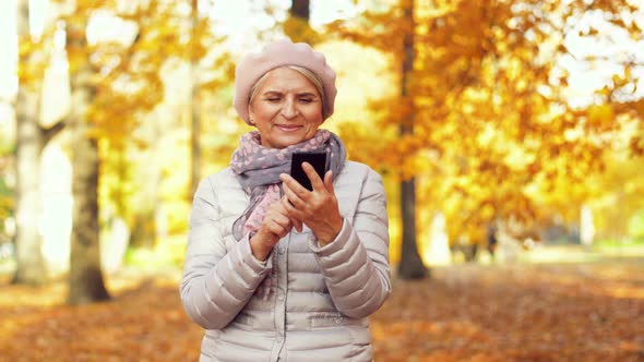 Happy Senior Woman with Smartphone at Autumn Park 12