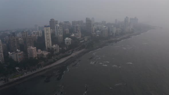 Rotating drone shot of Mumbai coastline on a hazy day high tide
