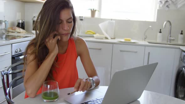 Young woman talking on mobile phone in kitchen at home 4k