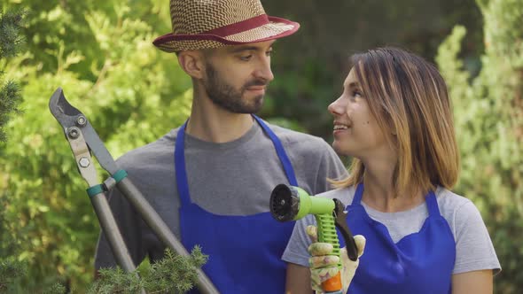 Portrait of Adorable Caucasian Woman and Handsome Man in Blue Uniform Standing in the Garden Holding