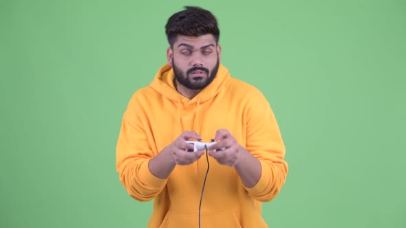 Tired Young Overweight Bearded Indian Man Playing Games and Falling Asleep