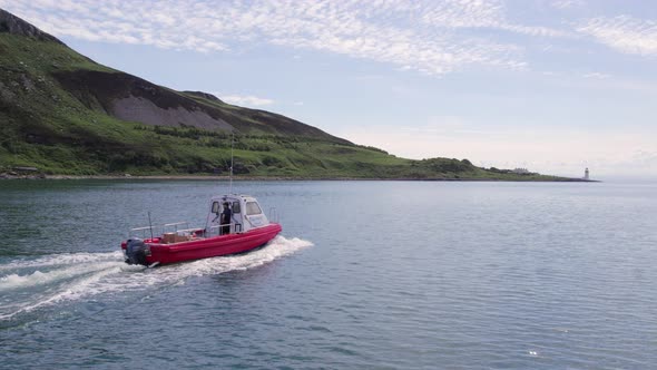 A Small Cargo Ferry at Sea Motoring Alongside an Island