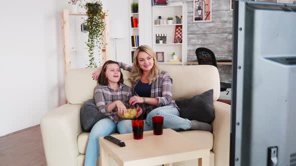 Happy Mother and Her Little Daughter Sitting on the Couch