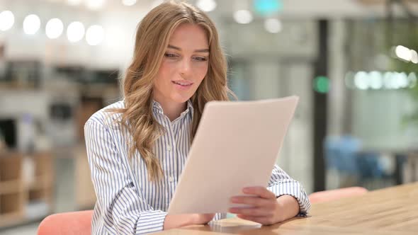 Excited Businesswoman Reading Documents and Celebrating in Office