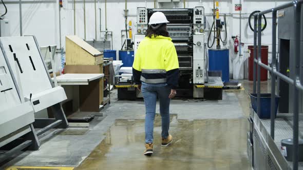 Back View of Female Machine Operator Walking at Factory