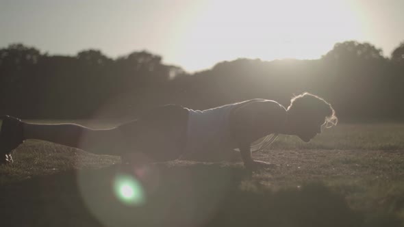 Man Doing Press Ups In The Park Against The Evening Sun