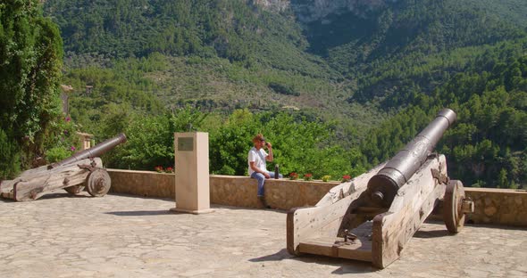 Male traveler resting and drinking coffee on ancient cannon