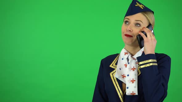 A Young Beautiful Stewardess Talks on a Smartphone with a Smile - Green Screen Studio