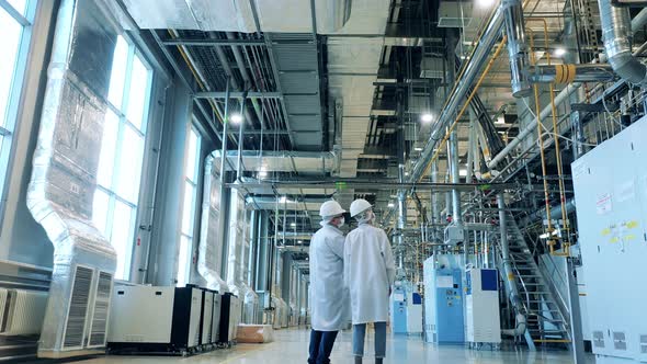 Two Specialists in Lab Coats are Walking Through the Factory Unit