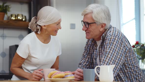 Senior Woman with Cancer and Her Husband Eating Breakfast and Talking at Home