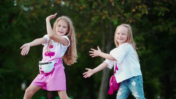 Kids In Park Outdoors. Two little happy girls dancing in park