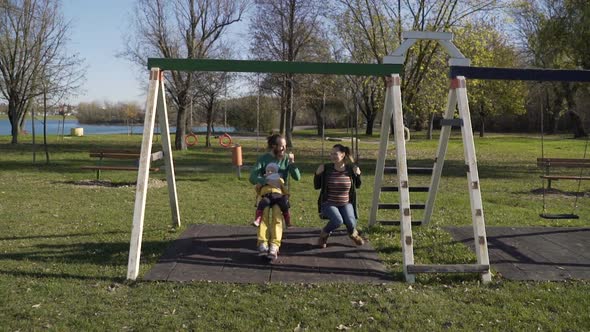 Family playing at swing in public playground, Zagreb, Croatia.