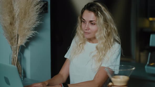 Smiling  Woman working at laptop in coffee shop. Female freelancer looking at screen