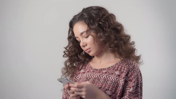 A sad upset girl with a phone in her hands is typing a message in a messenger