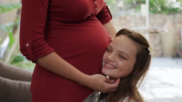 Daughter listening to the belly of her mother