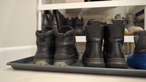 Family Winter Boots Lined Up on Hallway Rug Men Women and Tiny Baby Shoes
