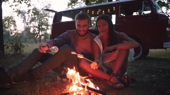 Beautiful Young Mixed Race Couple Roasting Marshmallows Over a Campfire While Enjoying Their Road