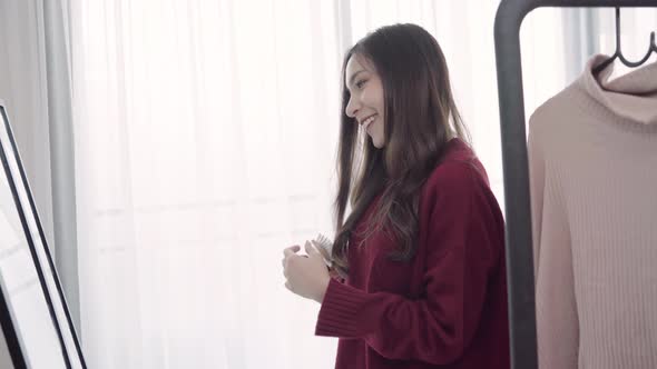 woman combing her hair and choosing clothes in her dressing room at home.