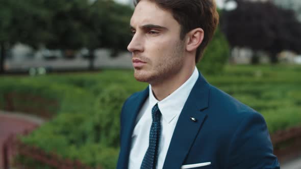 Serious Business Man Walking Past Public Garden