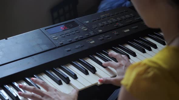 Long, Ultra High Definition, slow motion shot of an Asian woman practicing on a keyboard. Handheld o