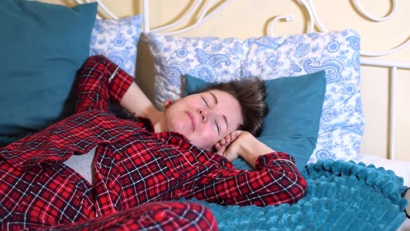 Young woman is waking up and stretching in bed