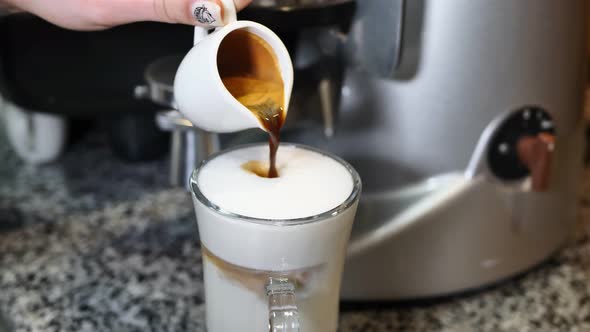 The Barista Pours Coffee Into a Cup with Milk on the Bar Table