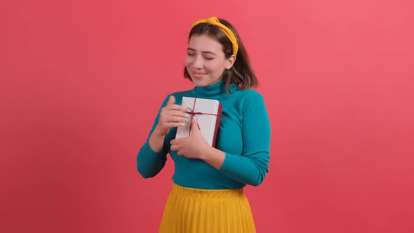 Joyful Woman Embracing Wrapped Gift Box and Smiling with Excitement, Rejoicing.