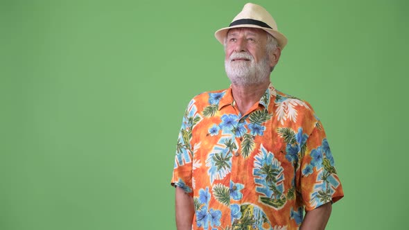 Handsome Senior Bearded Tourist Man Ready for Vacation Against Green Background