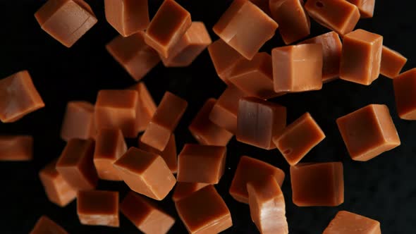 Super Slow Motion Shot of Caramel Pieces Exploded Towards Camera Isolated on Black at 1000Fps