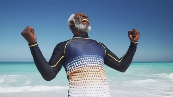 Senior man raising his arms at the beach