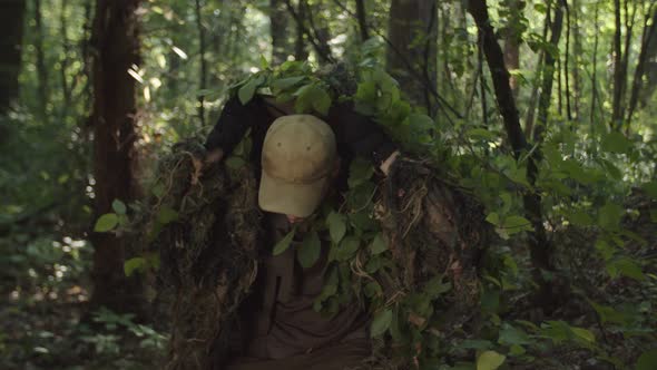 Military Sniper in Camouflage Getting Ready to Shoot in Forest at Dawn